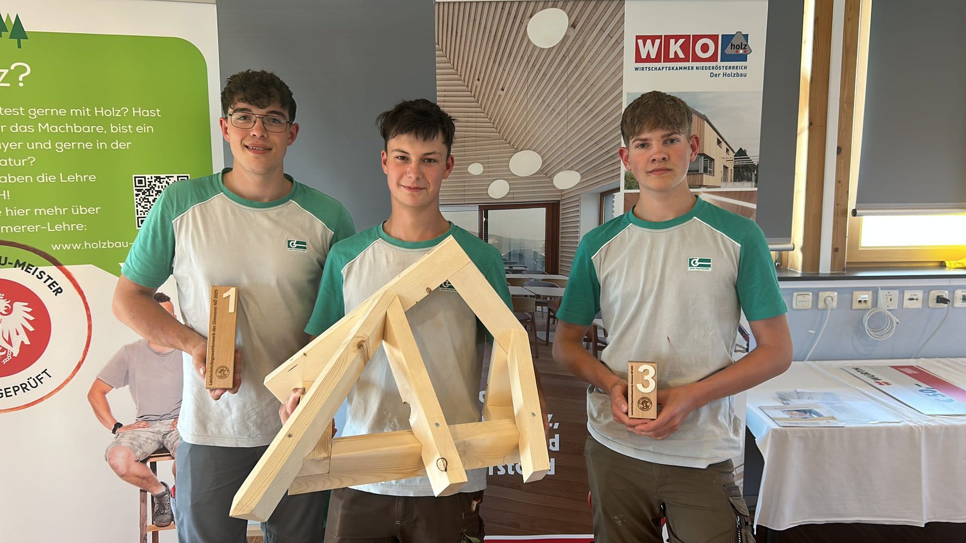 Drei Lehrlinge der Graf-Holztechnik zeigen deren Pokale sowie das Bauwerks welches im Rahmen des Landeslehrlingswettbewerb der Zimmerer erarbeitet wurde